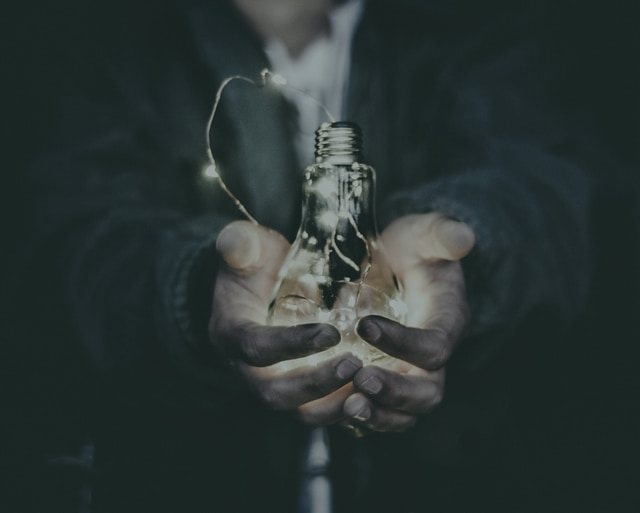 Hands holding a lit bulb
